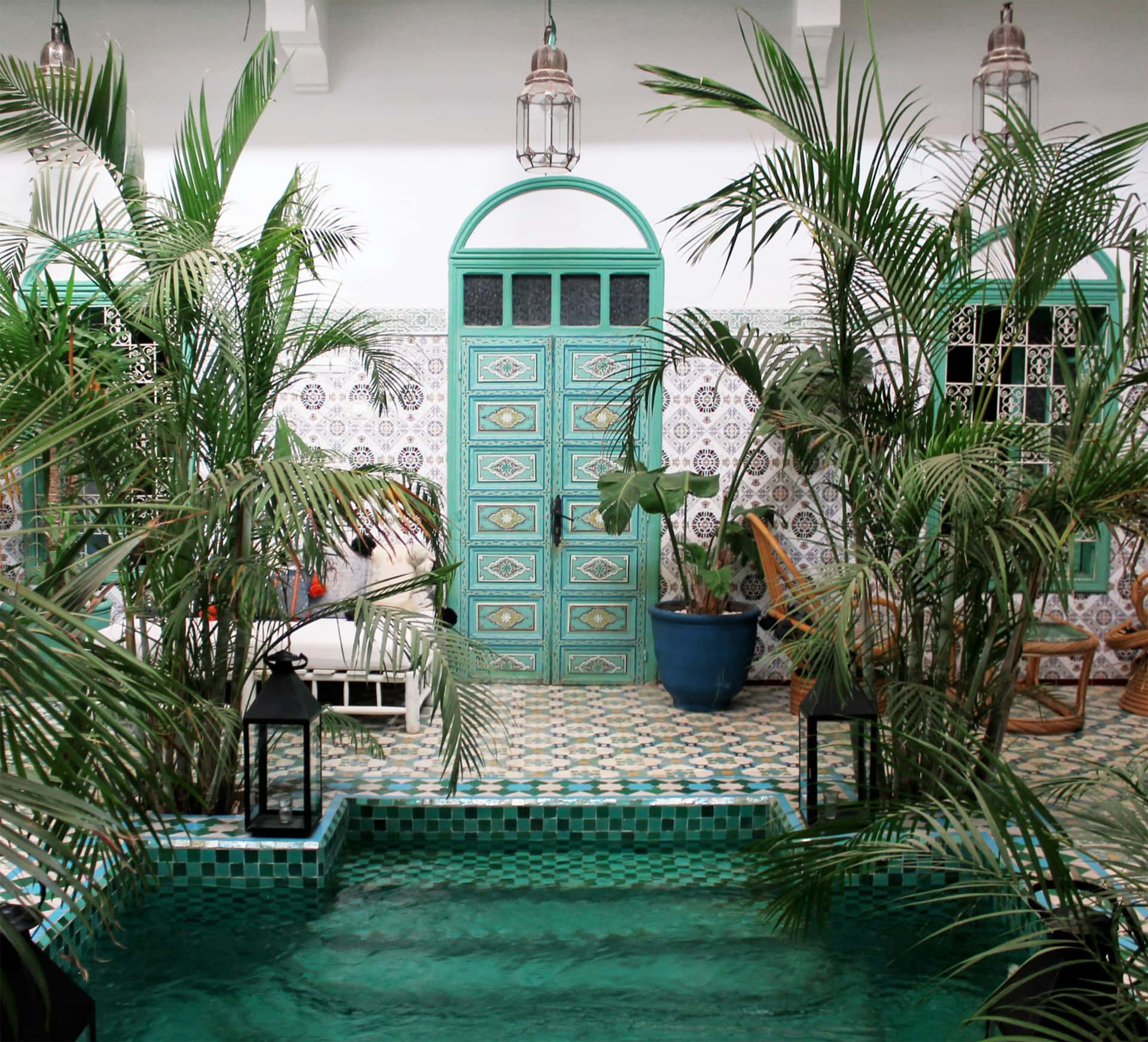 Patio de riad avec bassin, palmiers et porte verte